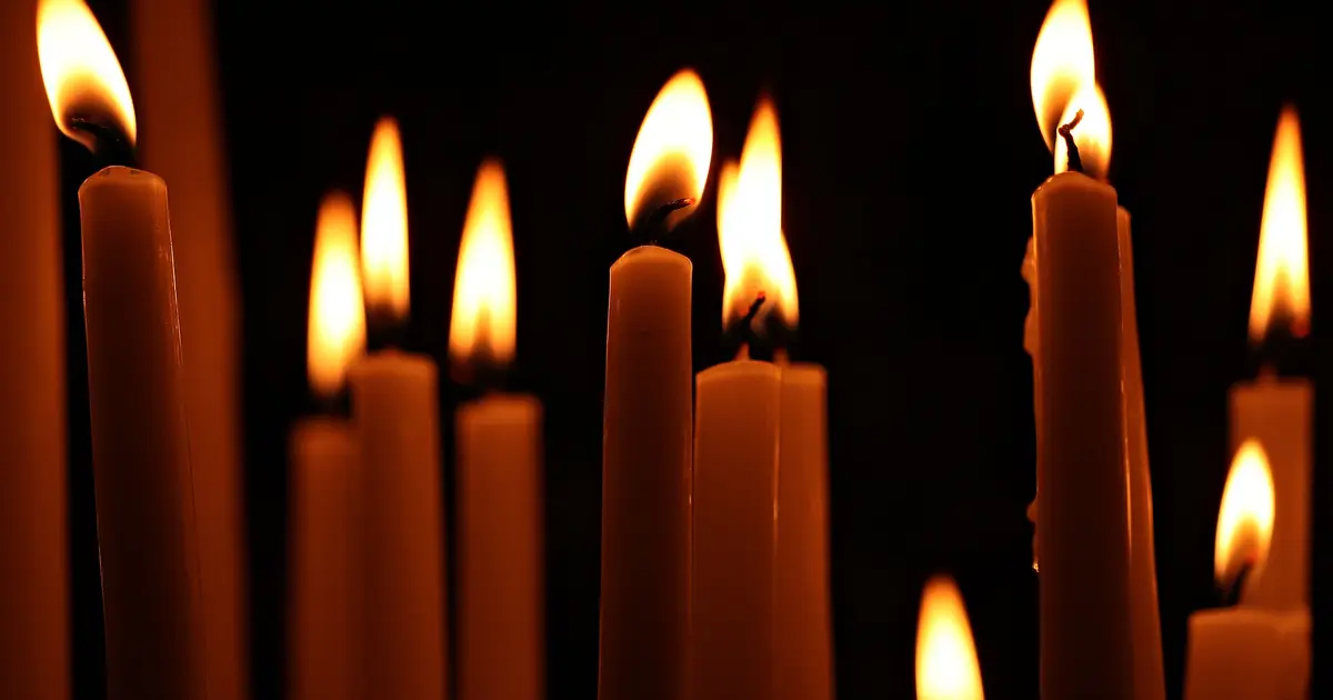 Een rij brandende kaarsen in het donker, zoals tijdens een stroomstoring